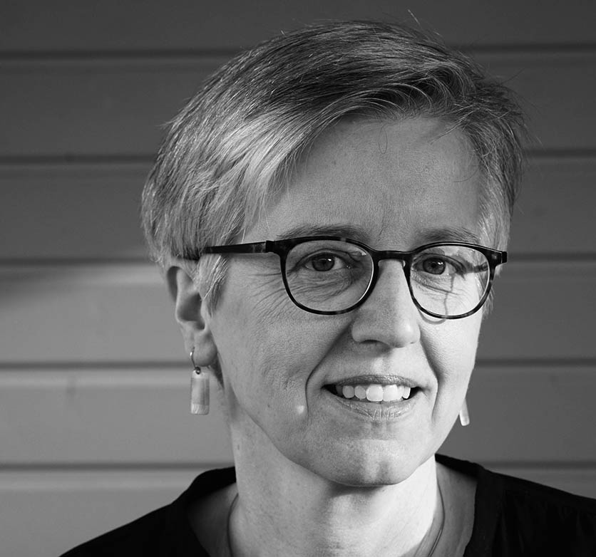Schwarz-weiß-Porträtfoto einer lächelnden weiblichen Person mit Brille